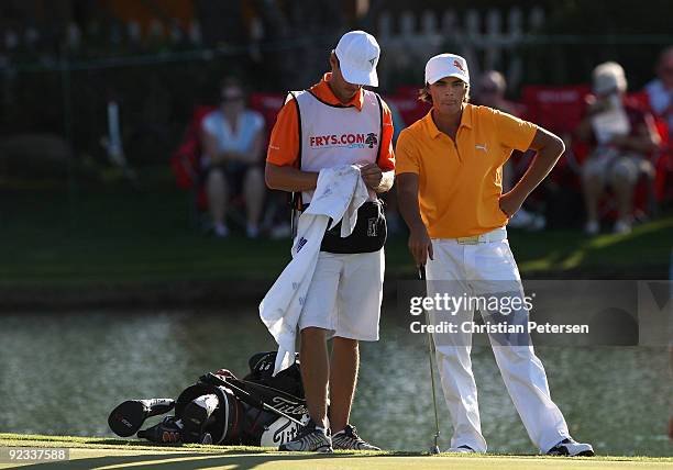 Rickie Fowler stands with his caddie Joe Skovron on the 18th hole green during the fourth round of the Frys.com Open at Grayhawk Golf Club on October...