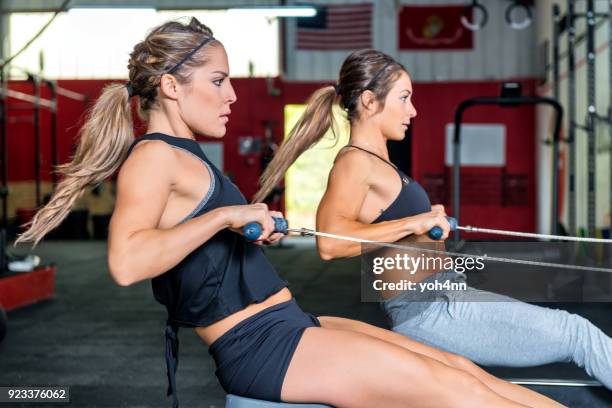 due donne che canottano con potenza in palestra - remare foto e immagini stock
