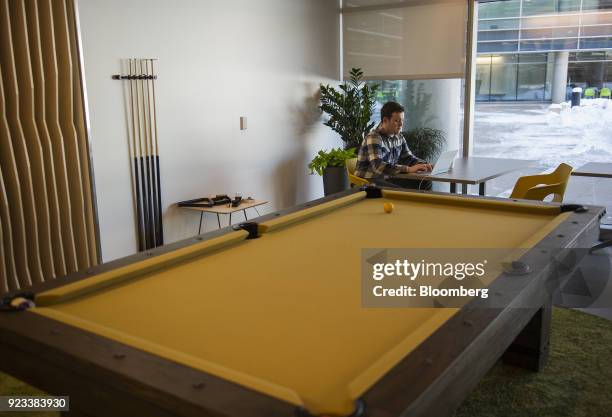 An employee works on a laptop computer while sitting next to a pool table at the new Google Inc. Campus in Boulder, Colorado, U.S., on Wednesday,...