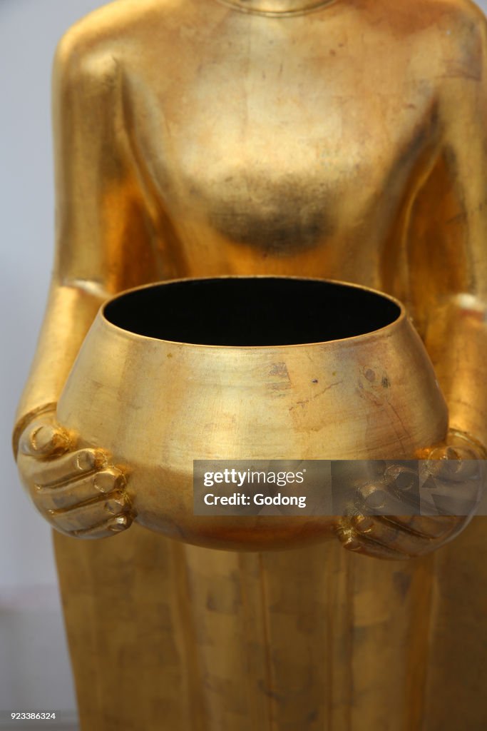 Detail of a statue depicting a Buddha with alm bowl.