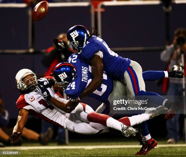 Larry Fitzgerald of the Arizona Cardinals loses the ball in a tackle by Terrell Thomas and C.C Brown breaks away from Hakeem Nicks of the New York...