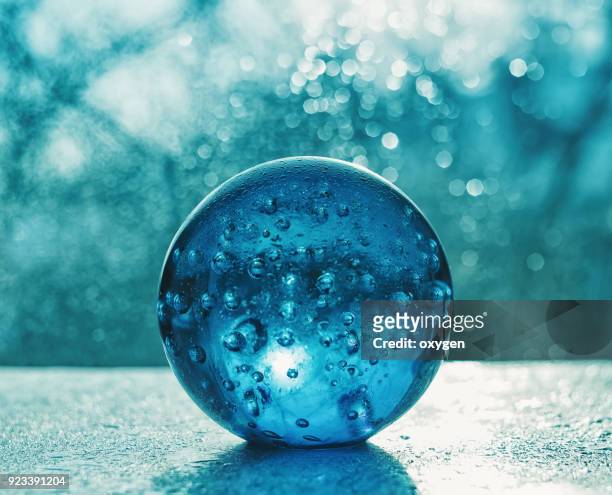 artistic composition of blue glass ball with water drop - magic ball stock-fotos und bilder