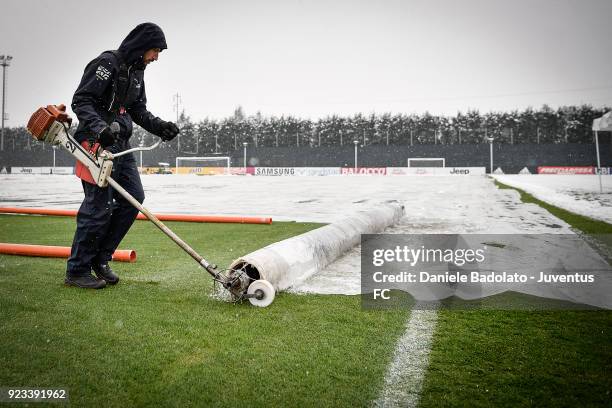 A worker removes the cover that protected the pitch from the snow during a Juventus training session at Juventus Center Vinovo on February 23, 2018...