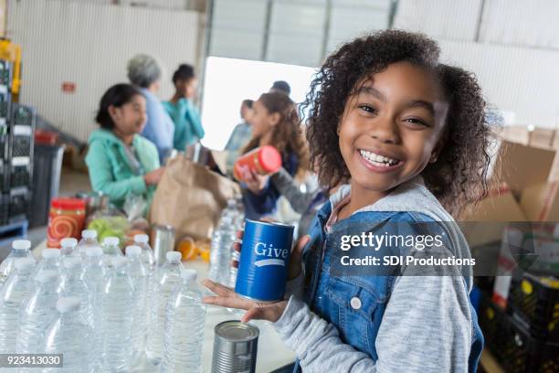 cheerful african american girl collects money during food drive - canned food drive stock pictures, royalty-free photos & images