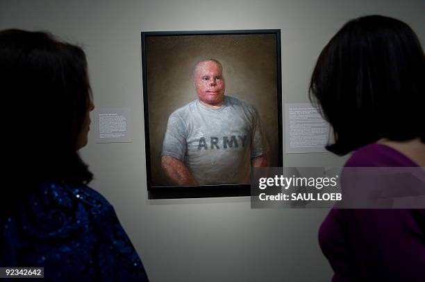 Visitors look at a painting of Rick Yarosh, a retired US Army Sergeant by artist Matthew Mitchell of Amherst, Massachusetts, prior to the opening of...