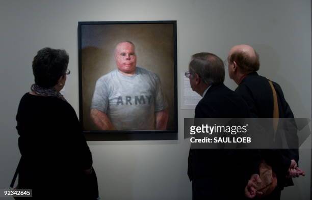 Visitors look at a painting of Rick Yarosh, a retired US Army Sergeant by artist Matthew Mitchell of Amherst, Massachusetts, prior to the opening of...