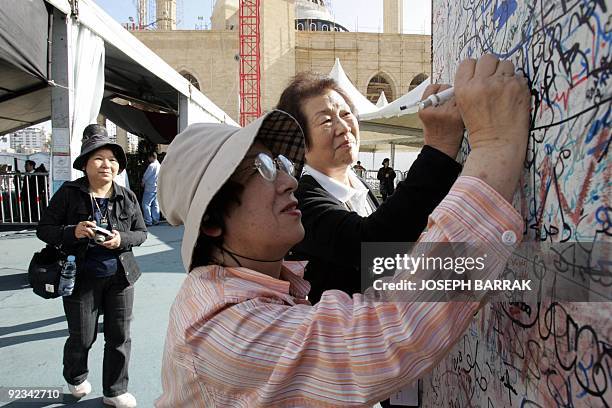 Japanese tourists sign 16 April 2005 on a wall of graffitti on Martyrs Square in Beirut, near the tomb of former prime minister Rafiq Hariri who was...