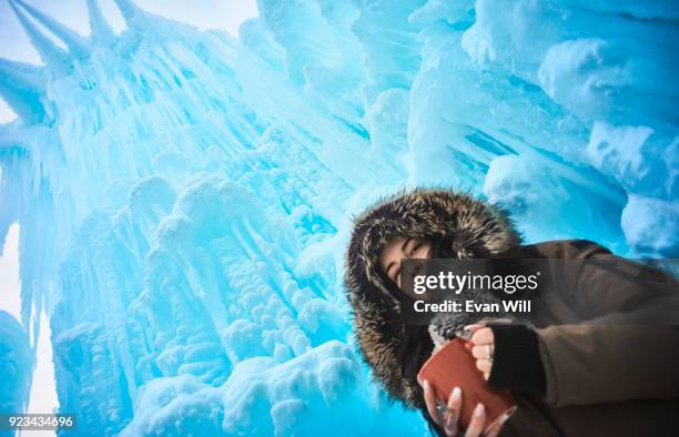 young woman smiling holding a red cup of tea smiling wearing a parka outside in the cold looking into the camera - edmonton winter stock pictures, royalty-free photos & images