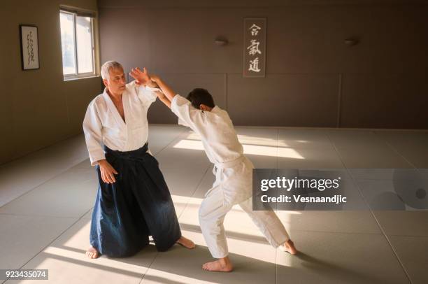 teen boy with his sansei practicing in dojo - aikido stock pictures, royalty-free photos & images