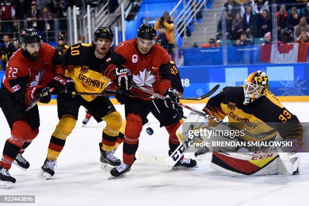 Canada's Eric O'Dell and Canada's Rene Bourque fight for the puck with Germany's Christian Ehrhoff in the men's semi-final ice hockey match between...