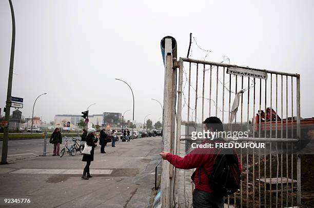 People take photos of a preserved segment of the Berlin wall at East Side Gallery on Berlin's Muhlen Strasse on October 25, 2009. Germany will...