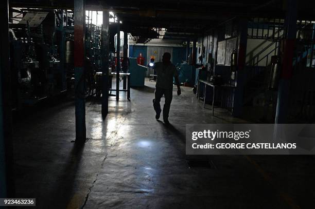 An employee of a printing press checks the machines during a power cut that began the day before in San Cristobal, Tachira state on February 23,...