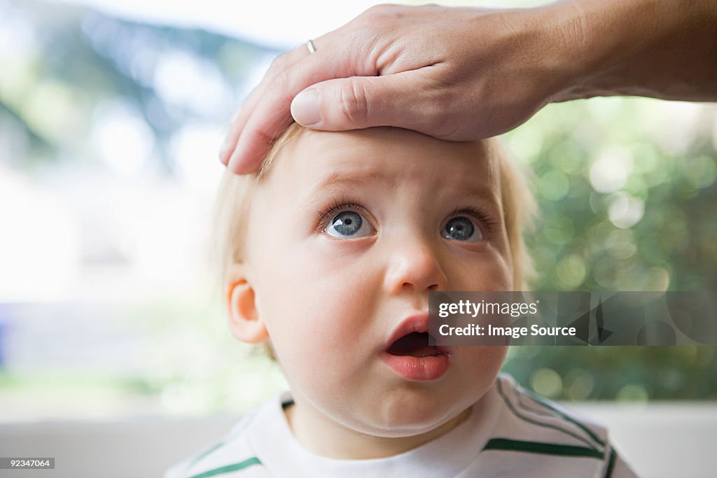 Adult hand on head of baby