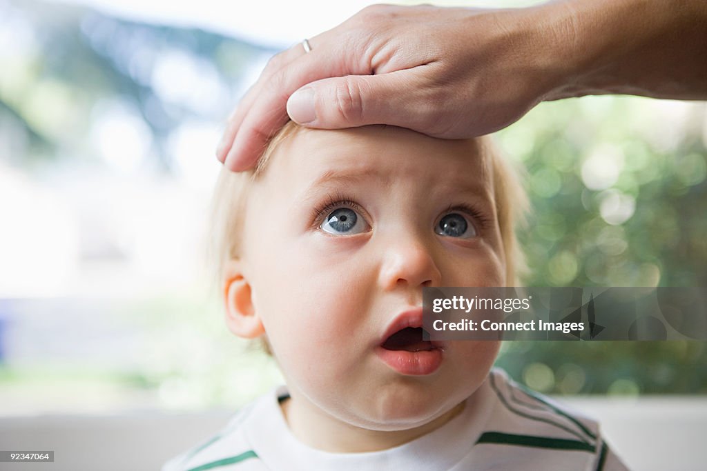 Adult hand on head of baby