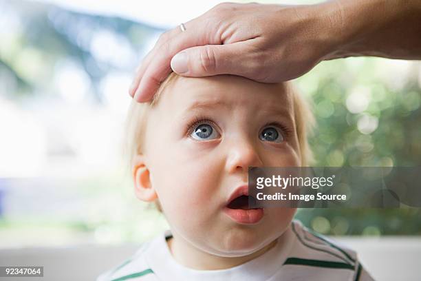 adult hand on head of baby - febre imagens e fotografias de stock
