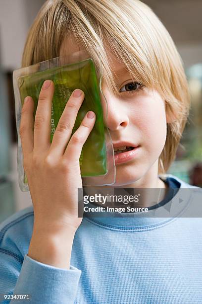 boy with ice pack on his eye - compresse stock-fotos und bilder