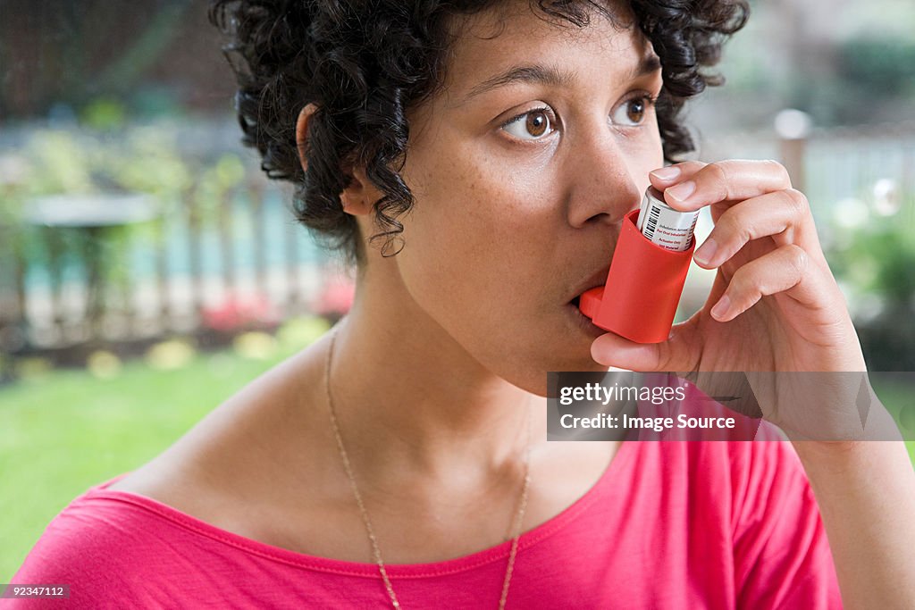 Woman taking asthma inhaler
