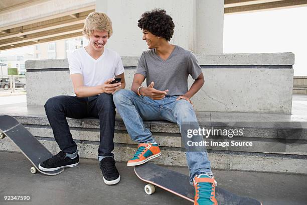 teenage boys with skateboards and cellphone - two boys talking stock-fotos und bilder