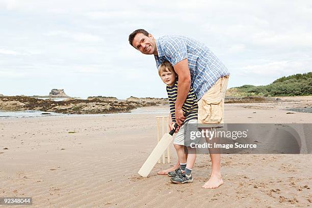 father and son playing cricket on beach - family cricket stockfoto's en -beelden