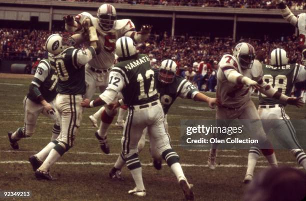 Quarterback Joe Namath of the New York Jets throws a pass during a game while under pressure from defensive lineman Arthur Moore and Mel Lunsford of...