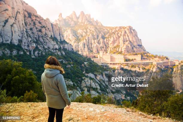 traveler woman contemplating the monastery of montserrat between the stunning rock formations mountain in catalonia. - catalonia stock pictures, royalty-free photos & images