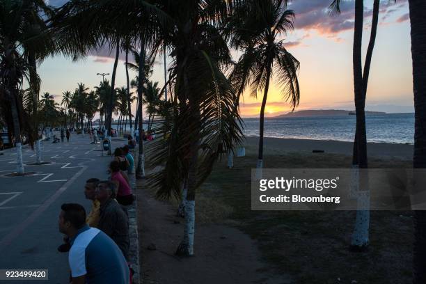 People sit on benches at Paseo Colon in Puerto La Cruz, Anzoategui state, Venezuela, on Wednesday, Feb. 7, 2018. Hunger is hastening the ruin of...