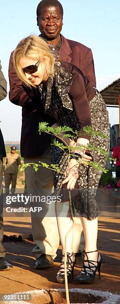 Pop queen Madonna holds a Moringa tree soon after planting it during a ceremony to officially launch the construction work of Madonna's Raising...