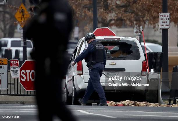 Member of a bomb squad inspects a vehicle that crashed into a barricade on the perimeter of the White House grounds February 23, 2018 in Washington,...