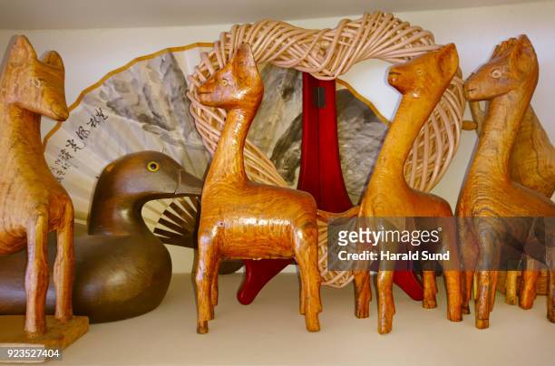 collection of hand made carved wood lamas, duck wicker heart and a hand fan displayed on a shelf.on a shelf. - wicker heart stock pictures, royalty-free photos & images