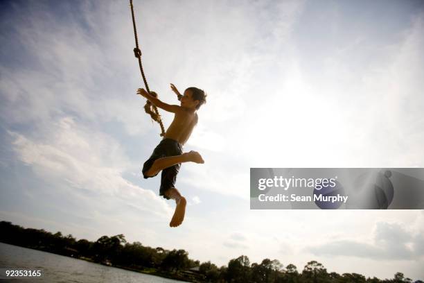 boy swinging on ropeswing - touwschommel stockfoto's en -beelden