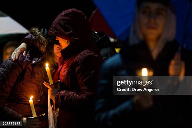 Mourners listen while names are read aloud during a community vigil at Newtown High School for the victims of last week's mass shooting at Marjory...