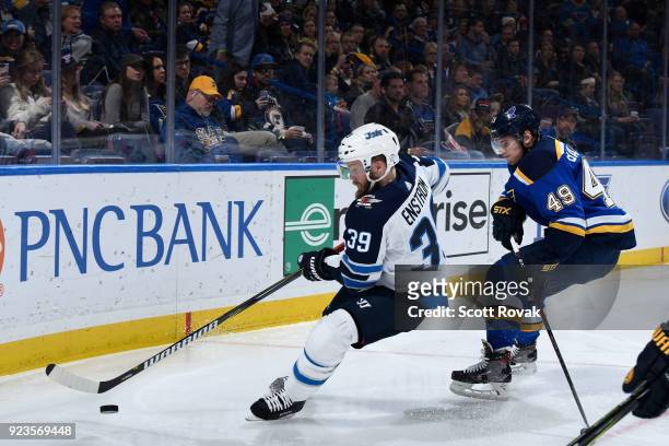 Toby Enstrom of the Winnipeg Jets controls the puck as Ivan Barbashev of the St. Louis Blues pressures at Scottrade Center on February 23, 2018 in...