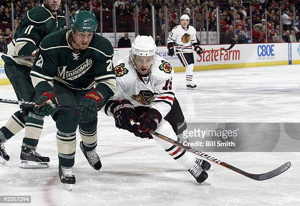 Kyle Brodziak of the Minnesota Wild and Andrew Ebbett of the Chicago Blackhawks skate towards the puck on October 26, 2009 at the United Center in...