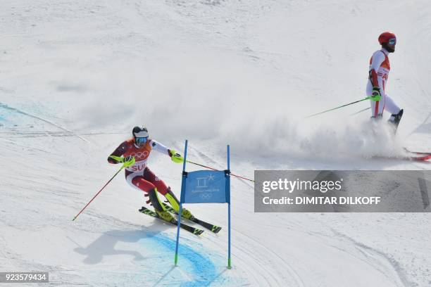 Switzerland's Daniel Yule advances to the finish-line as Austria's Marco Schwarz stops competing in the Alpine Skiing Team Event big final at the...