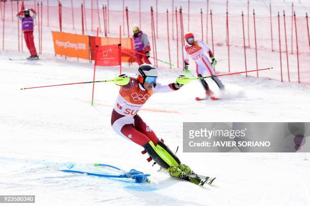 Switzerland's Daniel Yule advances to the finish-line as Austria's Marco Schwarz stops competing in the Alpine Skiing Team Event big final at the...