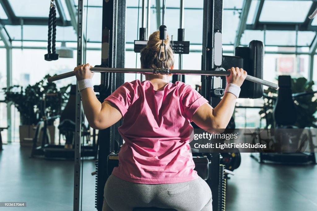 Overweight woman working out on training apparatus