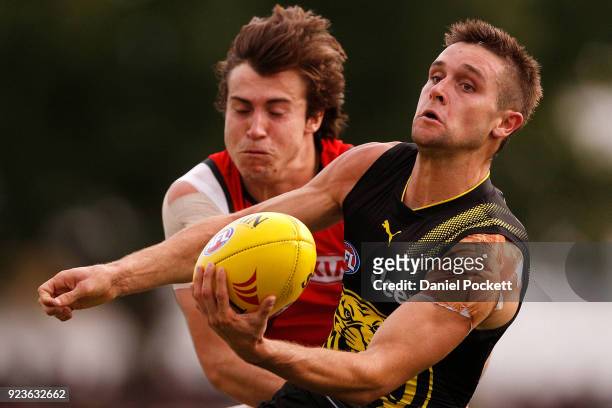 Jayden Short of the Tigers handpasses the ball whilst being tackled by Andrew McGrath of the Bombers during the JLT Community Series AFL match...