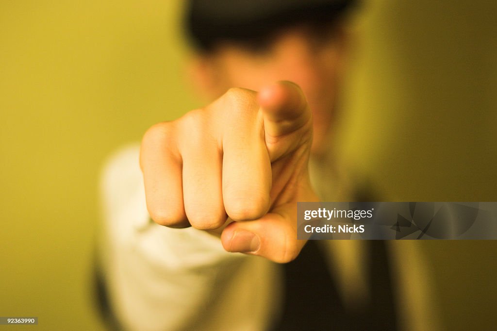 Detail of man pointing index finger on yellow background