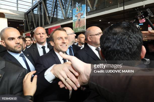French President Emmanuel Macron shakes hands as he visits the 55th International Agriculture Fair at the Porte de Versailles exhibition center in...