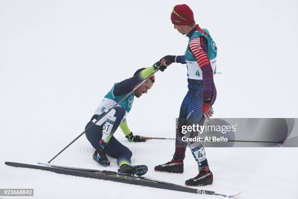 Noah Hoffman of the United States helps up Imanol Rojo of Spain after the Men's 50km Mass Start Classic on day 15 of the PyeongChang 2018 Winter...