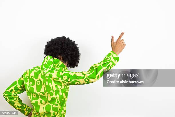 1970s styled disco dude points upward. - afro wig stock pictures, royalty-free photos & images