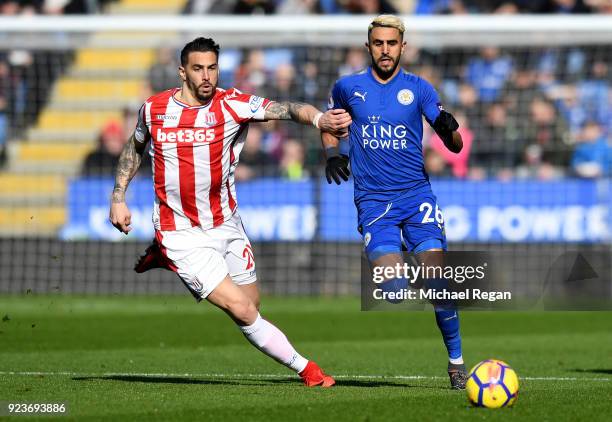 Riyad Mahrez of Leicester City is challenged by Geoff Cameron of Stoke City during the Premier League match between Leicester City and Stoke City at...