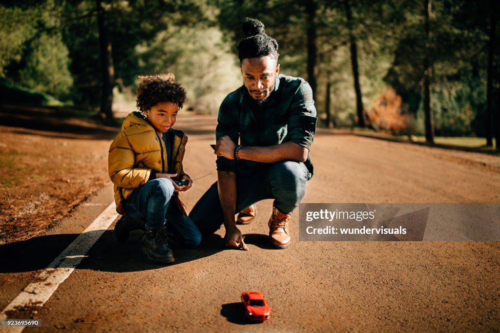 Padre e hijo jugando con coche control remota en la naturaleza