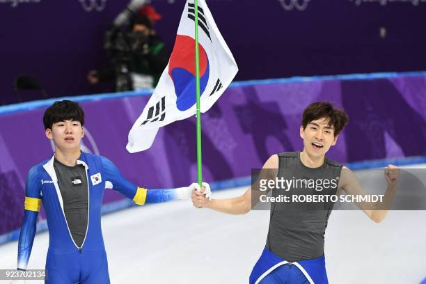 South Korea's Lee Seung-Hoon celebrates his gold medal win alongside compatriot Chung Jaewon, who finished eighth, in the men's mass start final...