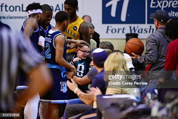 Fatts Russell of the Rhode Island Rams pats the head of a young fan who was run into after diving for the ball with the La Salle Explorers during the...