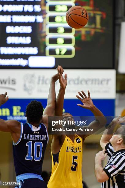 Cyril Langevine of the Rhode Island Rams and Tony Washington of the La Salle Explorers tipoff during overtime at Tom Gola Arena on February 20, 2018...