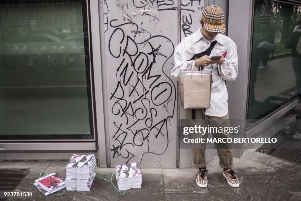 Man looks at his mobile phone as he arrives to attend the women's Fall/Winter 2018/2019 collection fashion show by Giorgio Armani in Milan, on...