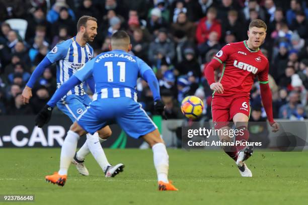 Alfie Mawson of Swansea City passes the ball past Glenn Murray and Anthony Knockaert of Brighton during the Premier League match between Brighton and...