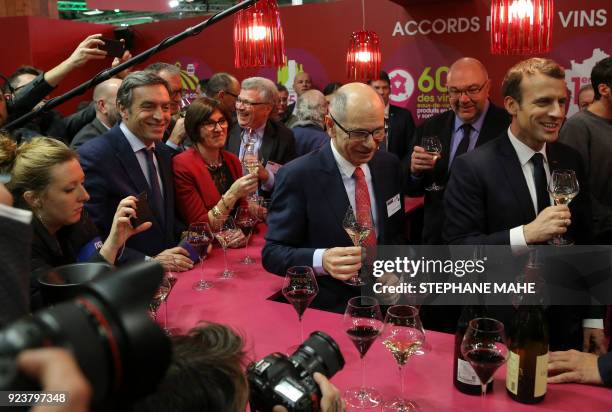 French President Emmanuel Macron , flanked by French Agriculture Minister Stephane Travert , holds a glass of white wine as he visits the 55th...