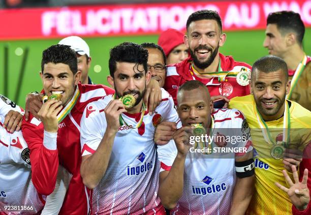 Wydad Casablanca's players bite their champions' medals as they celebrate after winning the 2018 Total CAF Super Cup match against TP Mazembe, at the...